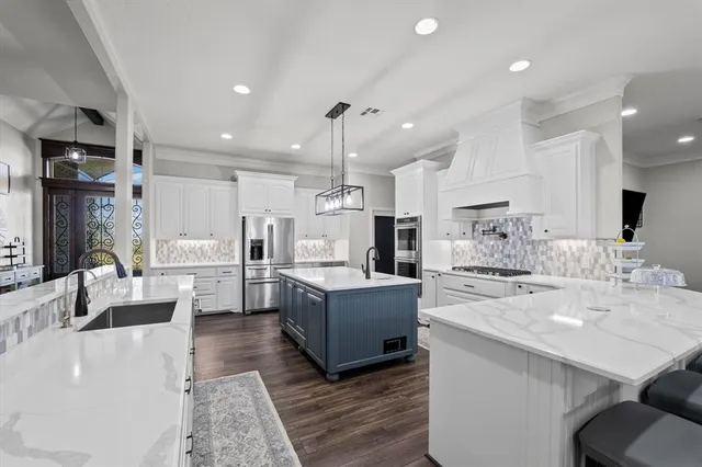 a large kitchen with cabinets counter top space a sink stainless steel appliances and cabinets