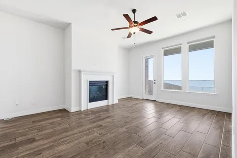 an empty room with wooden floor fan and windows