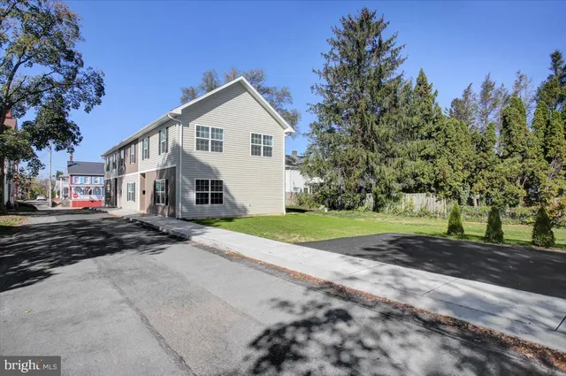 a view of a white house with a yard and large trees