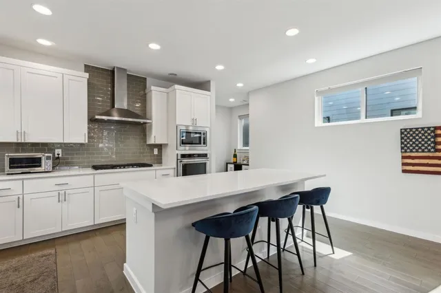 a kitchen with stainless steel appliances kitchen island granite countertop a table chairs sink and cabinets
