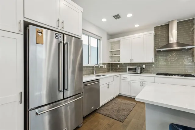 a kitchen with stainless steel appliances granite countertop a refrigerator a sink and white cabinets