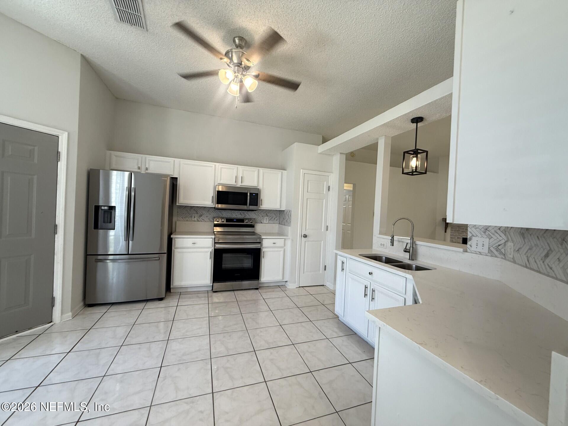 913 Mackinaw Trail St. Augustine, FL 32092 - Photo 17 of 65 a kitchen with stainless steel appliances a refrigerator sink cabinets and microwave