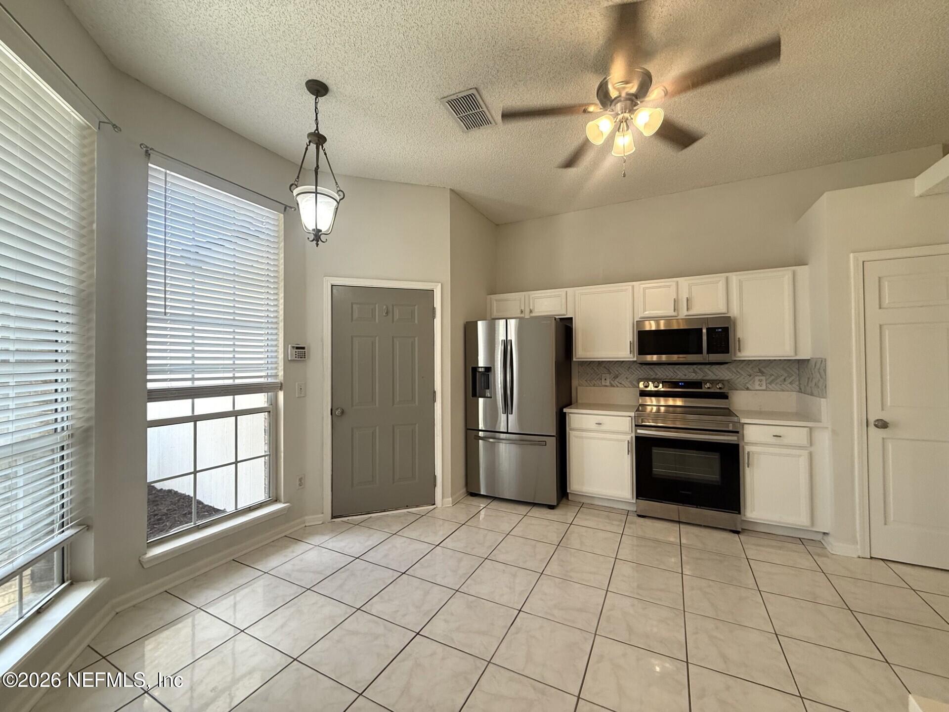 913 Mackinaw Trail St. Augustine, FL 32092 - Photo 21 of 65 a kitchen with stainless steel appliances granite countertop a refrigerator and a stove top oven