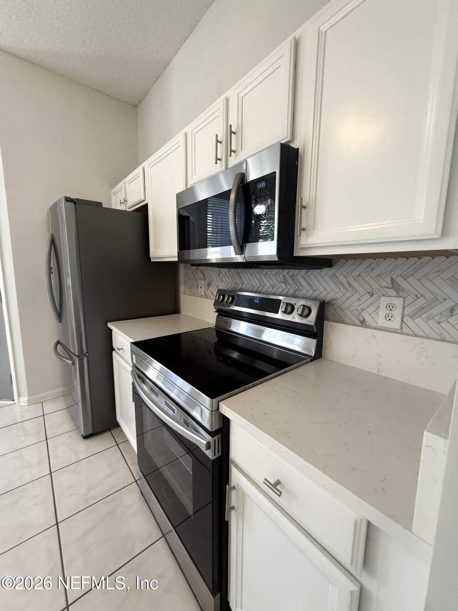 913 Mackinaw Trail St. Augustine, FL 32092 - Photo 28 of 65 a kitchen with stainless steel appliances a stove microwave and white cabinets
