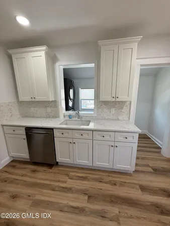 a kitchen with granite countertop a sink cabinets and wooden floor