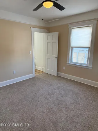 a view of an empty room with window and chandelier fan