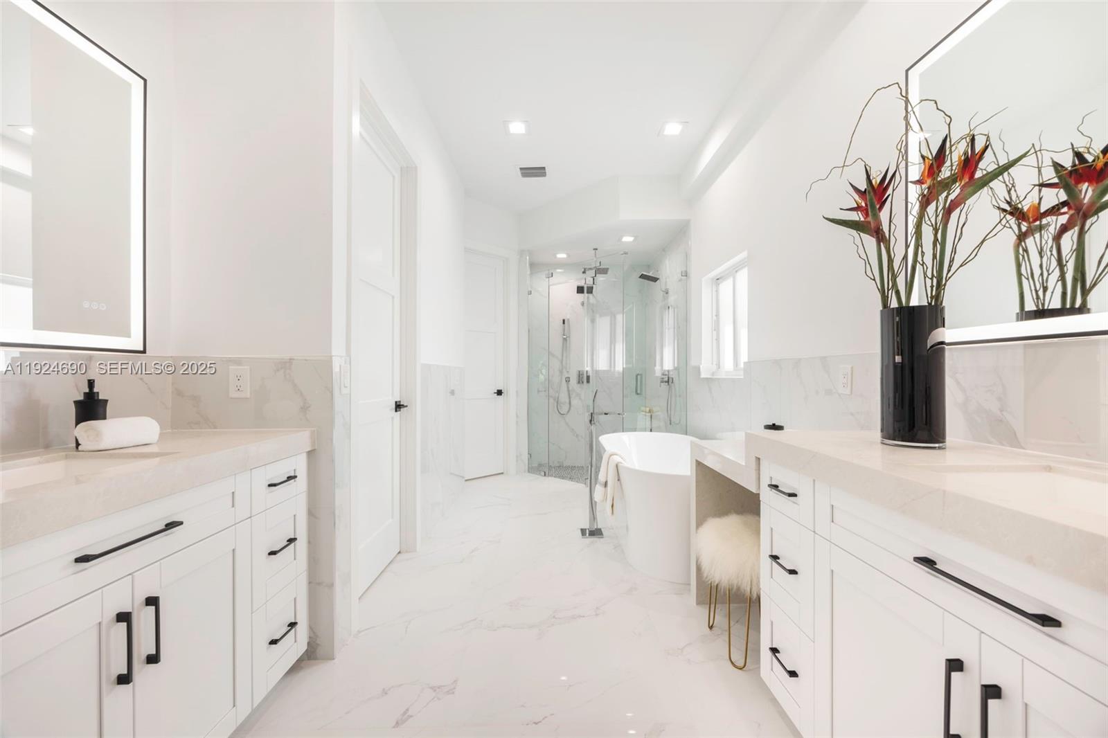 6845 Southwest 52nd Street Miami, FL 33155 - Photo 28 of 39 a spacious bathroom with a double vanity sink a mirror and a bathtub
