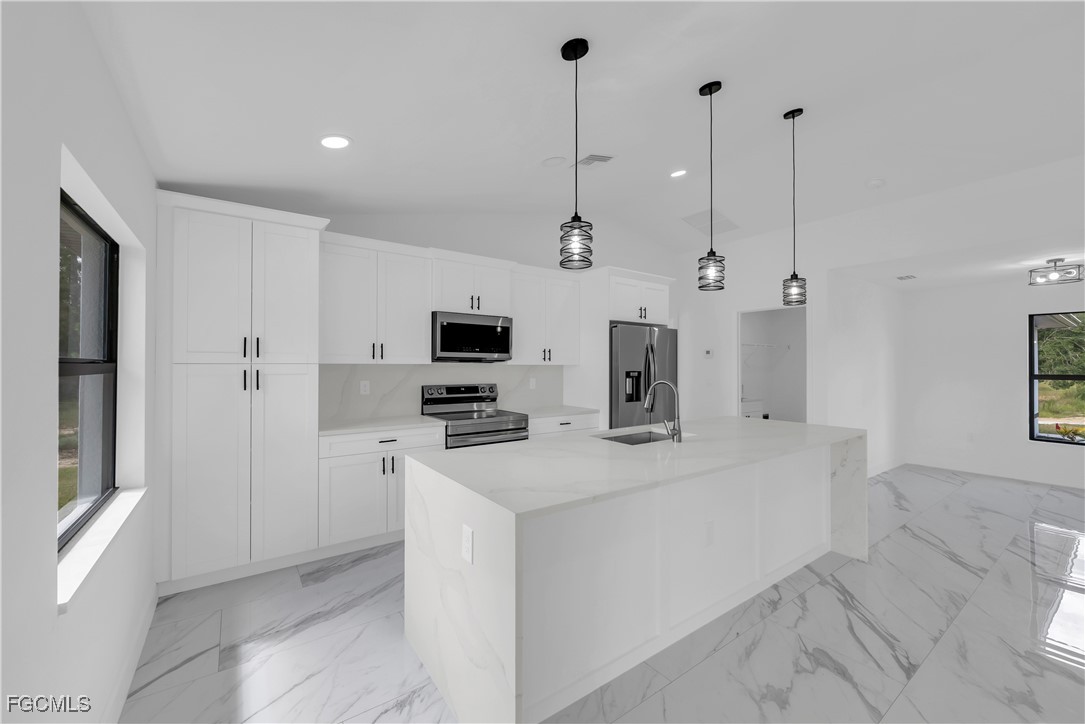 7602 18th Place LaBelle, FL 33935 - Photo 11 of 30 a view of a kitchen with stainless steel appliances kitchen island a sink dishwasher a refrigerator with white cabinets and wooden floor