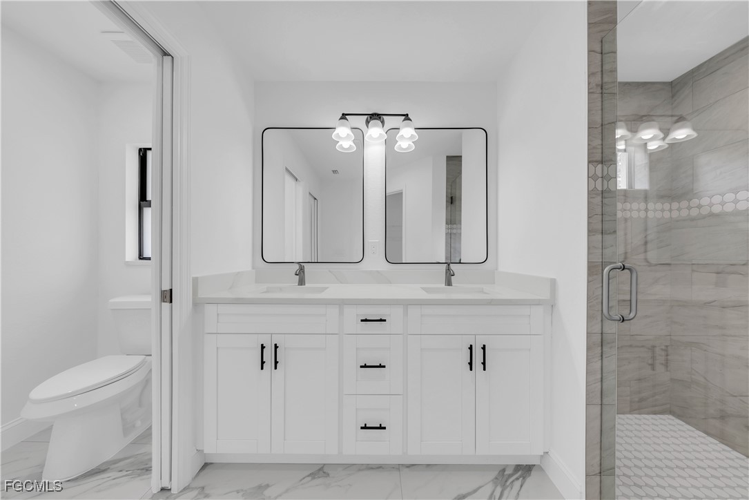 7602 18th Place LaBelle, FL 33935 - Photo 15 of 30 a bathroom with a double vanity sink toilet and shower