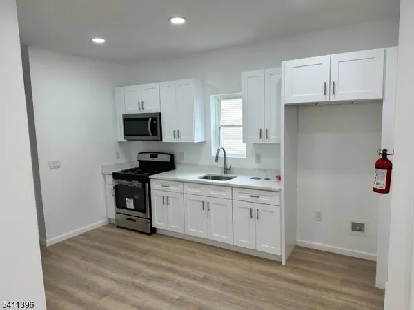 a kitchen with granite countertop a stove a sink and a refrigerator