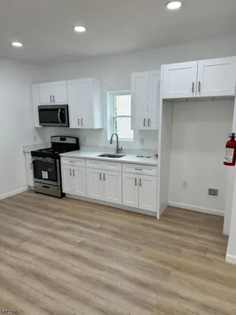 a kitchen with stainless steel appliances granite countertop a stove top oven a sink and white cabinets
