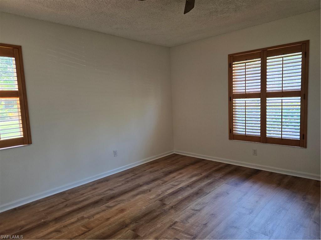 5737 Whitaker Road, Unit C104 Naples, FL 34112 - Photo 23 of 35 Wood-finish flooring throughout master bedroom, complemented by light-toned walls and dual windows featuring wood plantation shutters