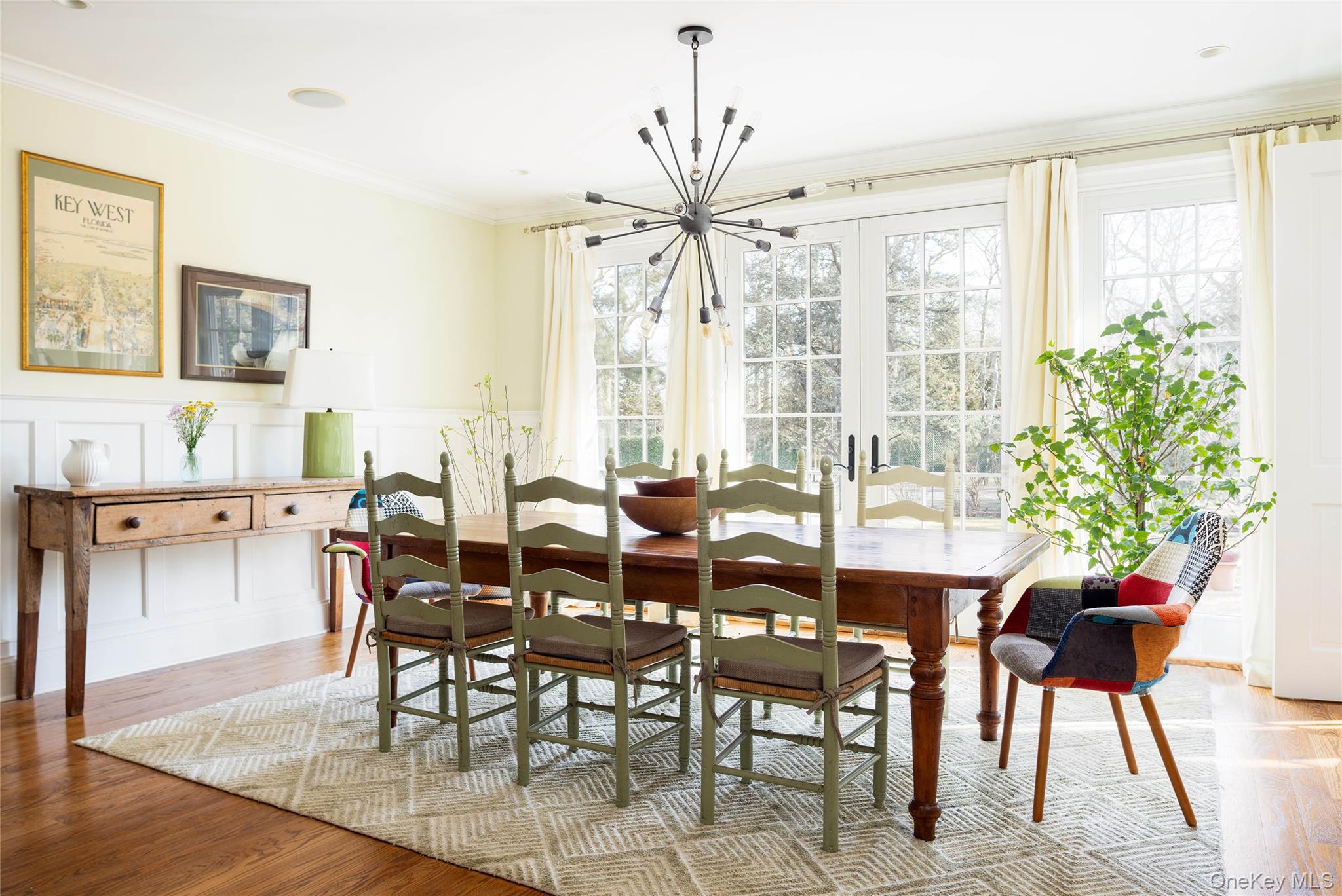 53 Cedar Lane West Remsenburg, NY 11960 - Photo 21 of 38 Dining area featuring a wainscoted wall, wood finished floors, a decorative wall, ornamental molding, and an inviting chandelier