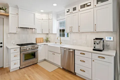 a kitchen with cabinets stainless steel appliances and wooden floor