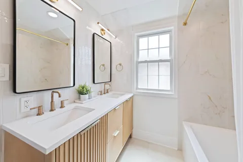 a bathroom with a double vanity sink a mirror and a bathtub