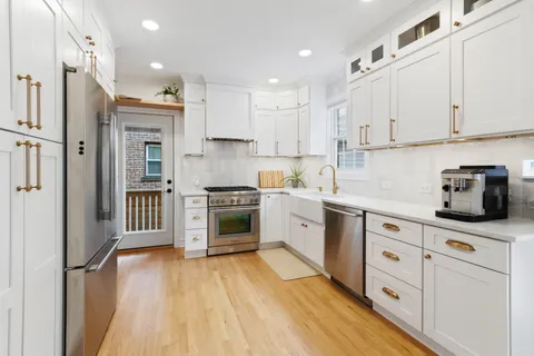 a kitchen with stainless steel appliances white cabinets and wooden floors
