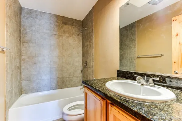 a bathroom with a granite countertop sink toilet and shower