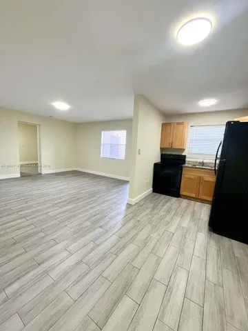 a view of a livingroom with wooden floor and kitchen space