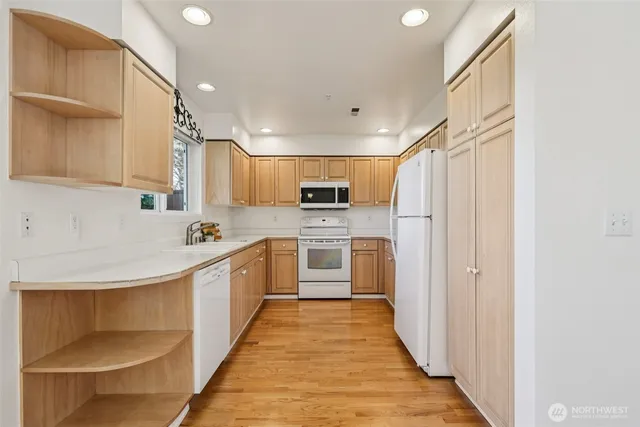 a view of a kitchen with a sink and dishwasher a refrigerator with wooden floor