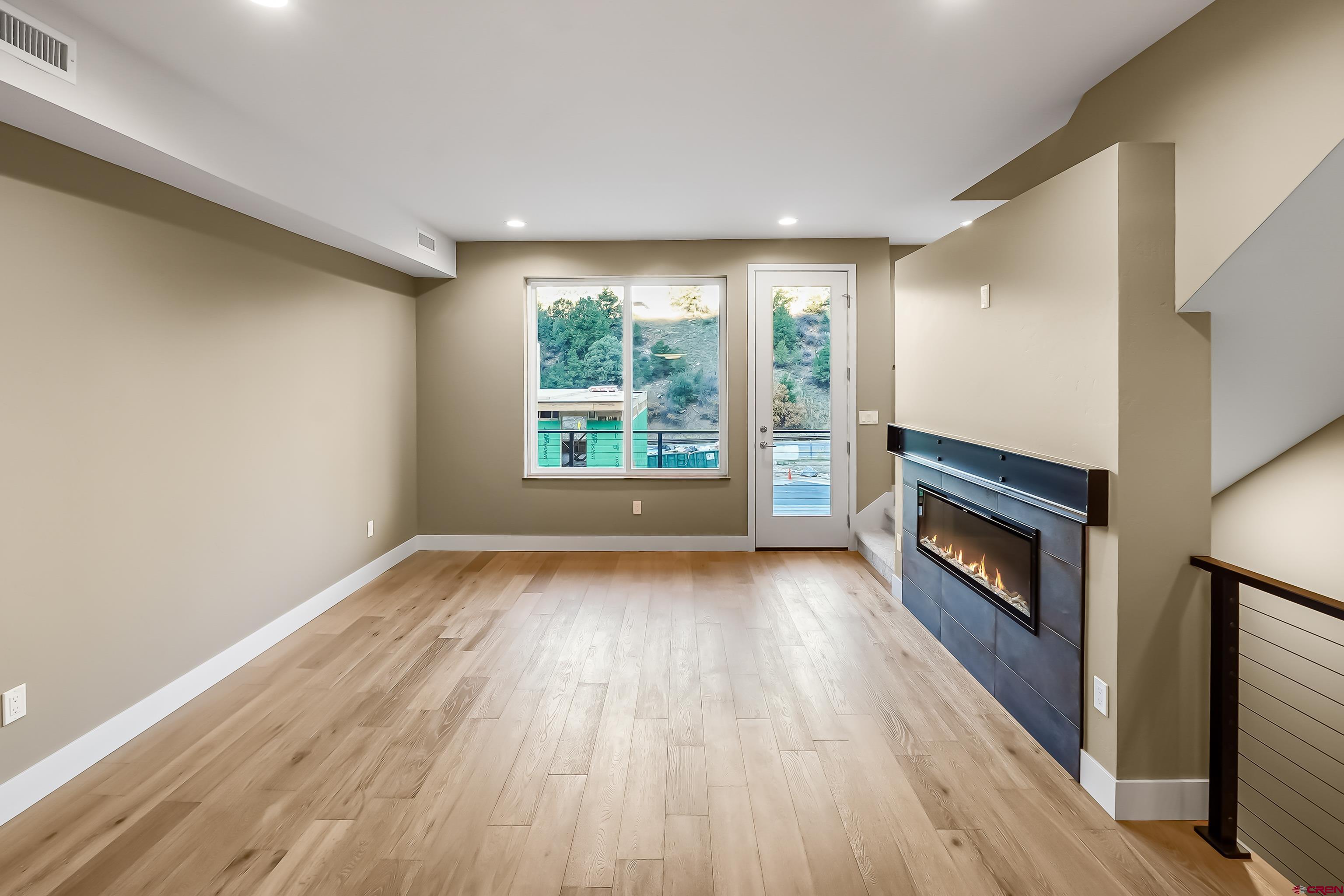762 Goeglein Gulch Road, Unit 5 Durango, CO 81301 - Photo 17 of 43 a view of an empty room with wooden floor fireplace and a window