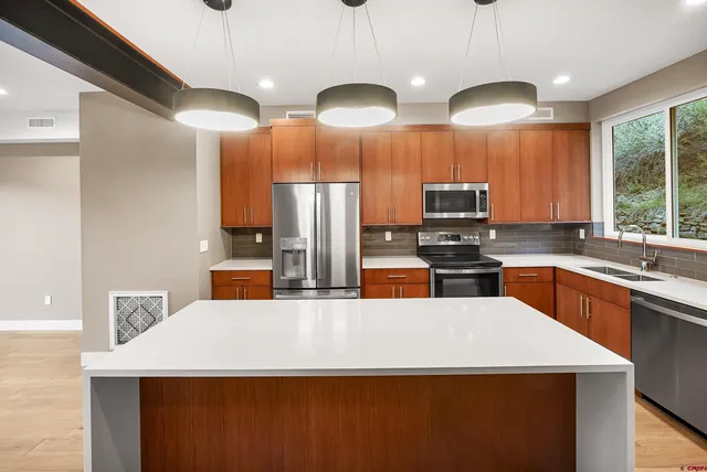 a kitchen with stainless steel appliances a refrigerator a sink a stove a center island a stove and a sink