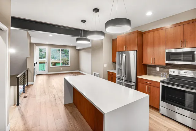 a kitchen with stainless steel appliances a stove a refrigerator a sink and dishwasher with wooden floor