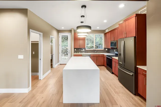 a kitchen with stainless steel appliances granite countertop a refrigerator a stove and a wooden floors