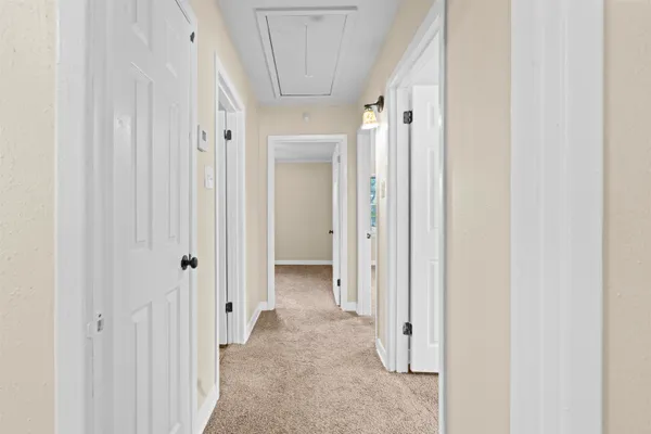 a view of a hallway with white walls and door