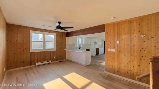 a view of empty room with wooden floor and fan