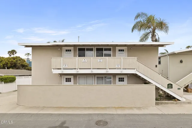 a view of a white house with a yard and palm trees