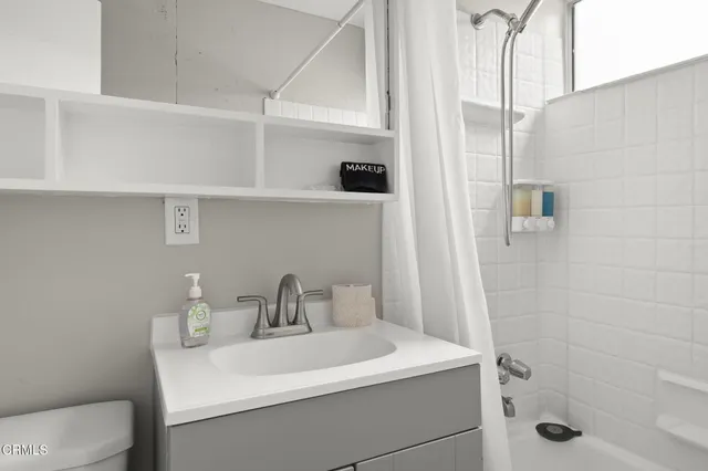 a kitchen with granite countertop a stove a sink and white cabinets with wooden floor