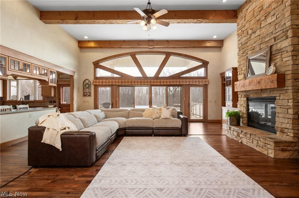 9419 Robinson Road Chardon, OH 44024 - Photo 3 of 49 Spacious living area featuring high vaulted ceilings with exposed wood beams, a stone-faced fireplace with a wood mantel, and expansive windows with an arched transom