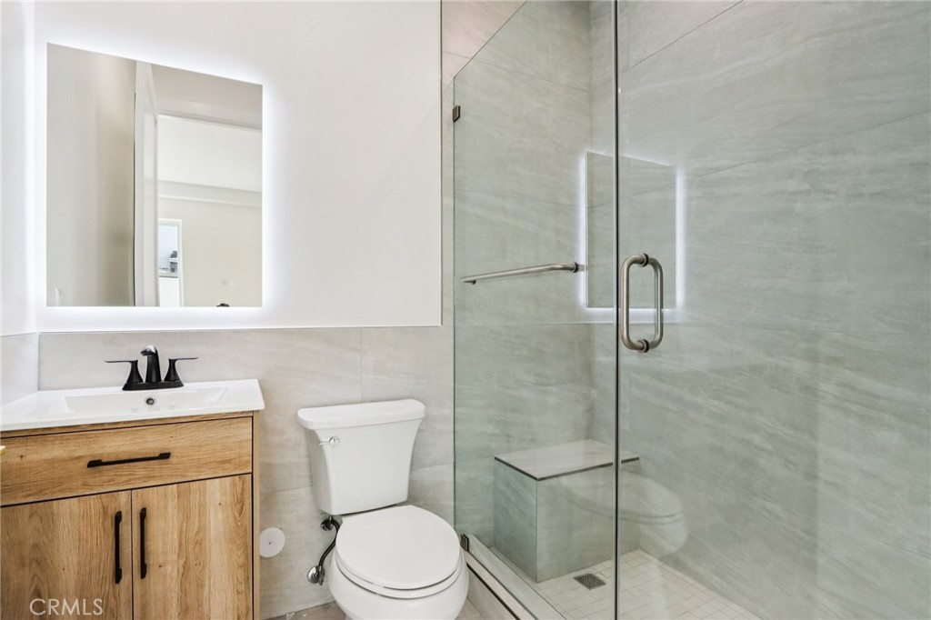 14931 Vose Street Van Nuys, CA 91405 - Photo 16 of 51 a bathroom with a toilet sink vanity and shower