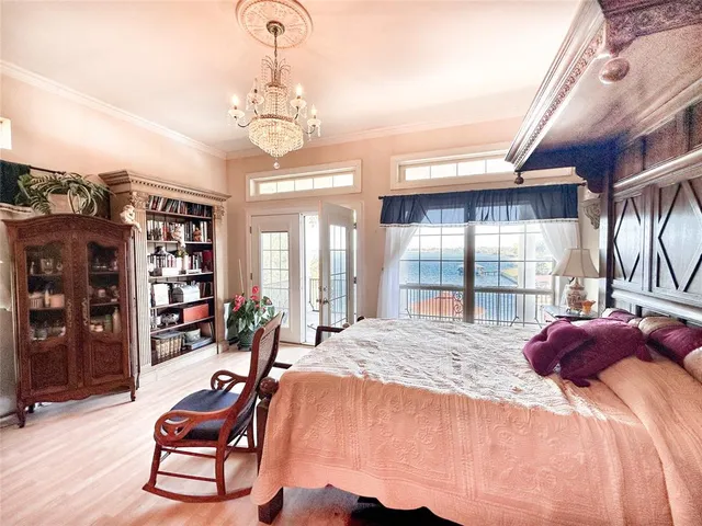 a bedroom with a bed a chandelier and large window