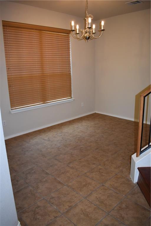 1310 West Parmer Lane, Unit 1503 Austin, TX 78727 - Photo 17 of 26 Empty room with hanging lights and dark tile patterned flooring