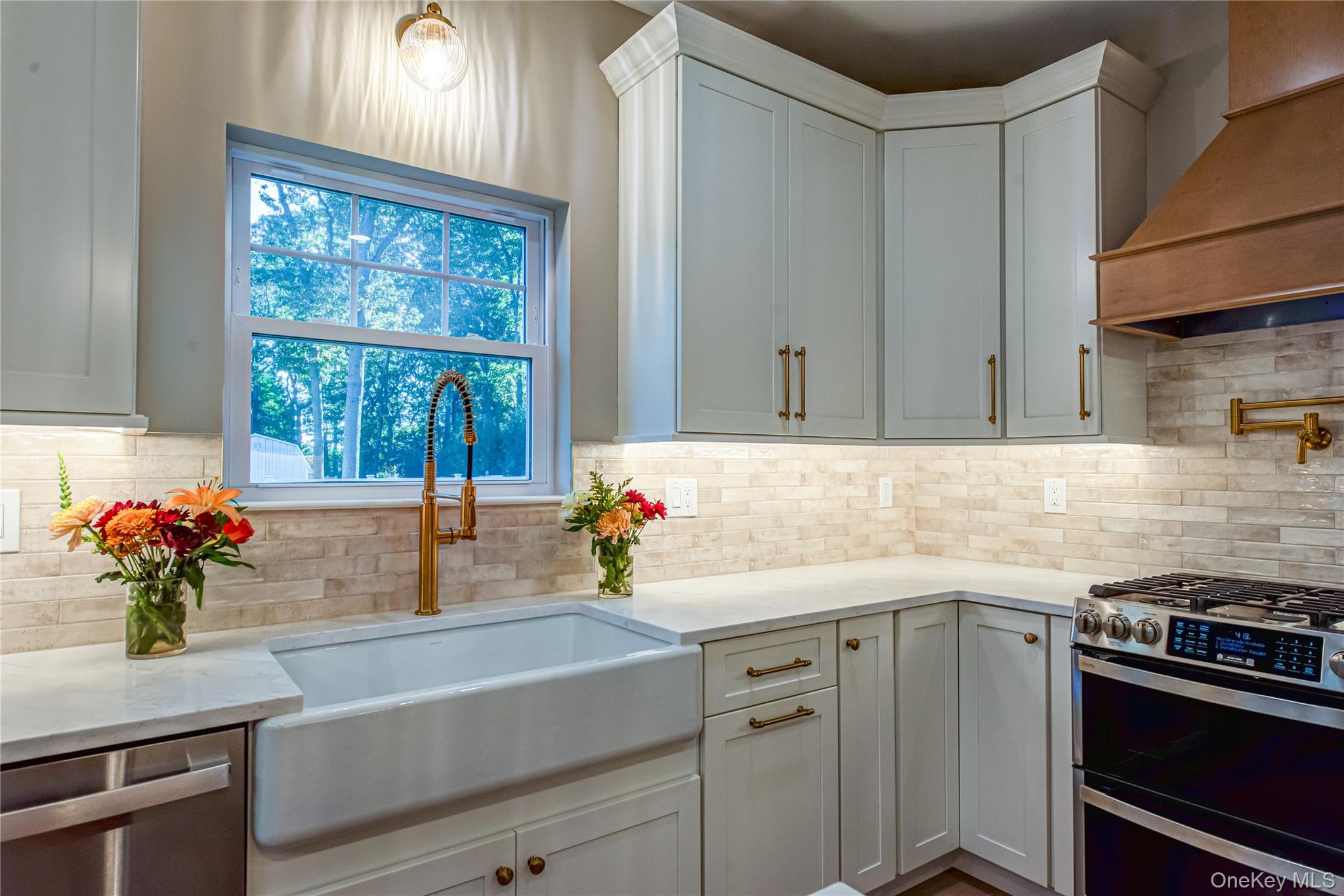 64 Blydenburgh Road Centereach, NY 11720 - Photo 25 of 44 Kitchen featuring stainless steel appliances, custom range hood, light stone countertops, white cabinets, and backsplash. For Marketing Purposes!