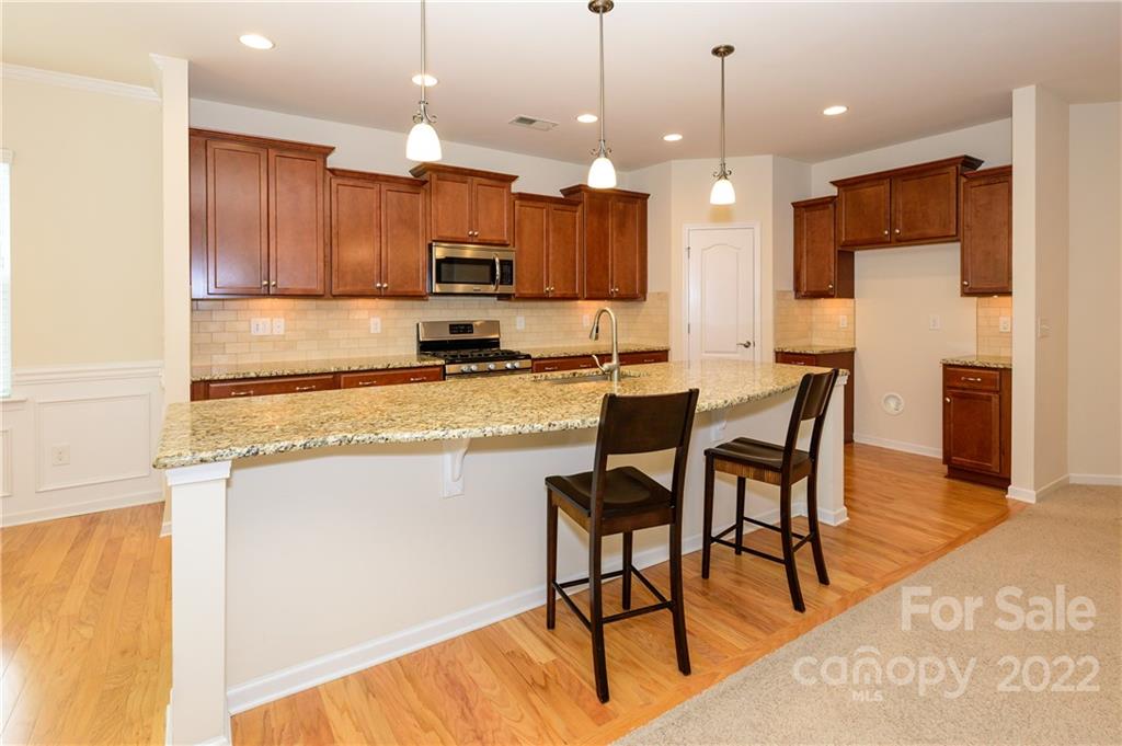 4241 Perth Road Indian Land, SC 29707 - Photo 5 of 34 a kitchen with stainless steel appliances kitchen island granite countertop a stove a refrigerator a kitchen island a dining table and chairs with wooden floor