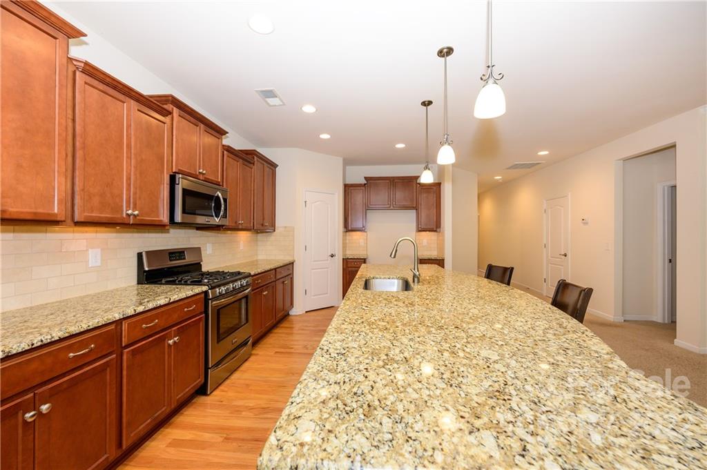 4241 Perth Road Indian Land, SC 29707 - Photo 6 of 34 a large kitchen with kitchen island granite countertop a stove a sink dishwasher and a refrigerator with wooden floor