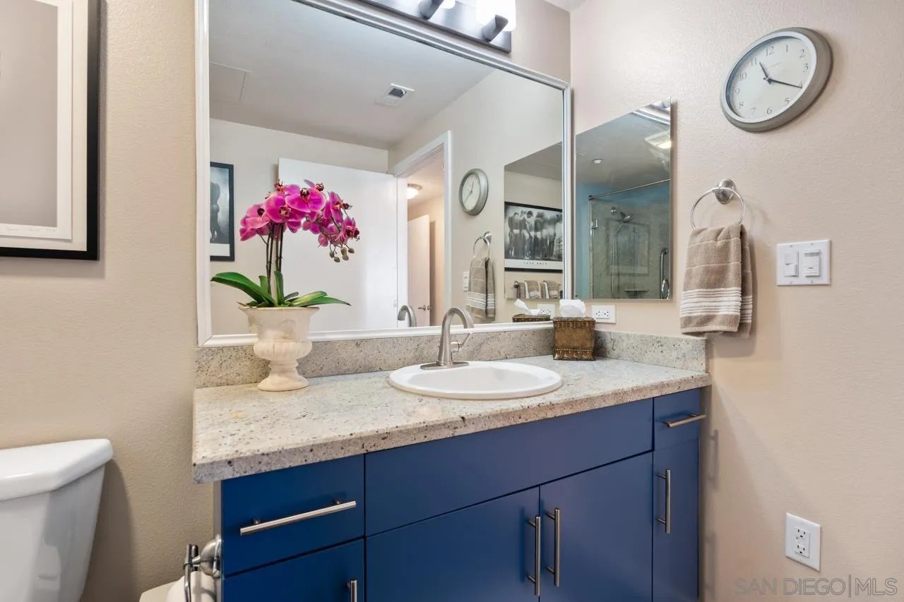 3650 Fifth Avenue, Unit 614 San Diego, CA 92103 - Photo 48 of 62 a bathroom with a granite countertop sink a mirror and a toilet