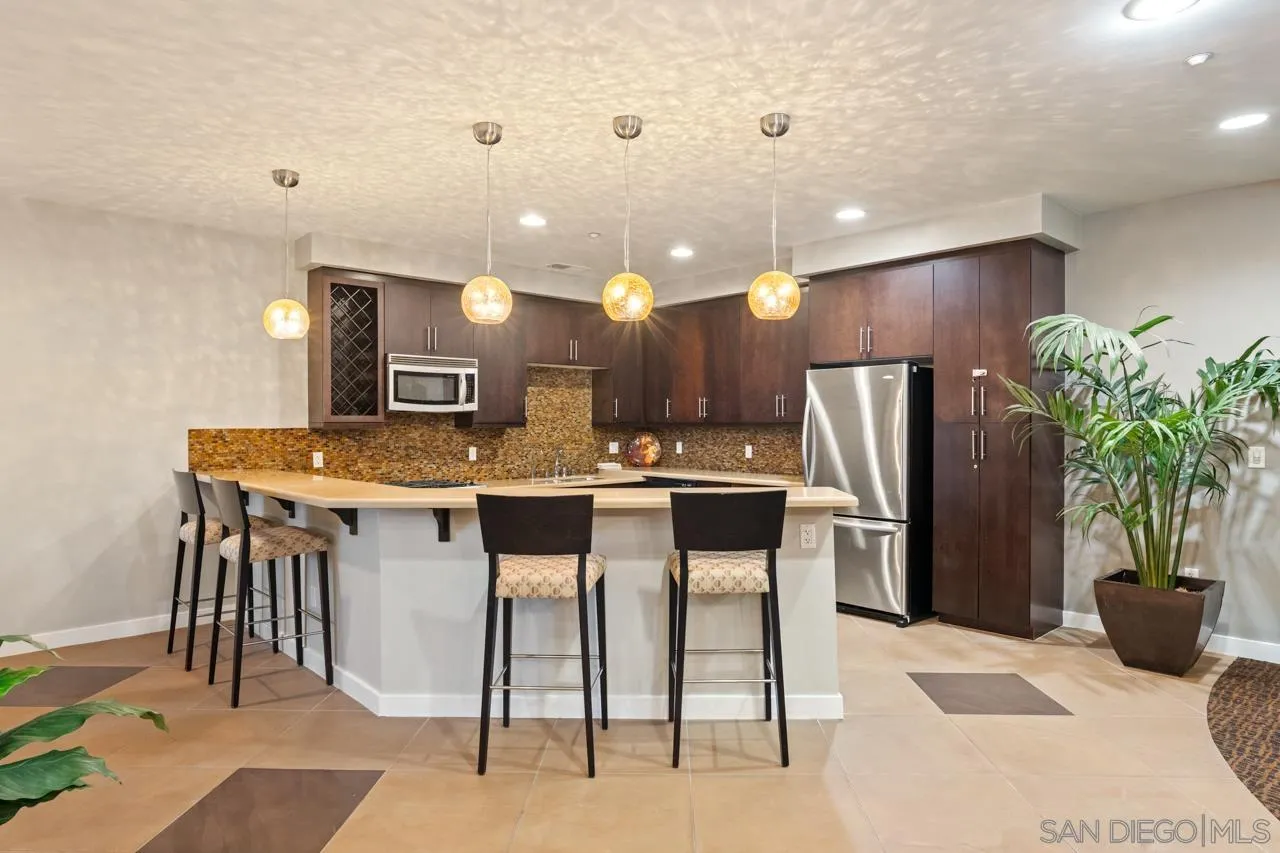 3650 Fifth Avenue, Unit 614 San Diego, CA 92103 - Photo 54 of 62 a kitchen with stainless steel appliances kitchen island granite countertop a refrigerator and a sink