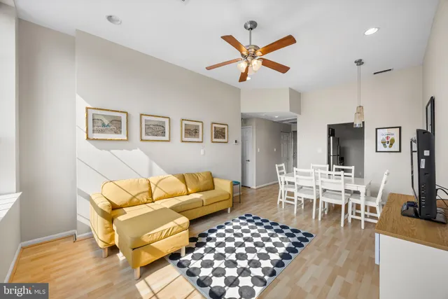 a living room with furniture kitchen view and a wooden floor