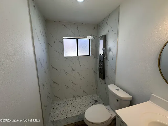 a white toilet sitting next to a bathroom sink and vanity