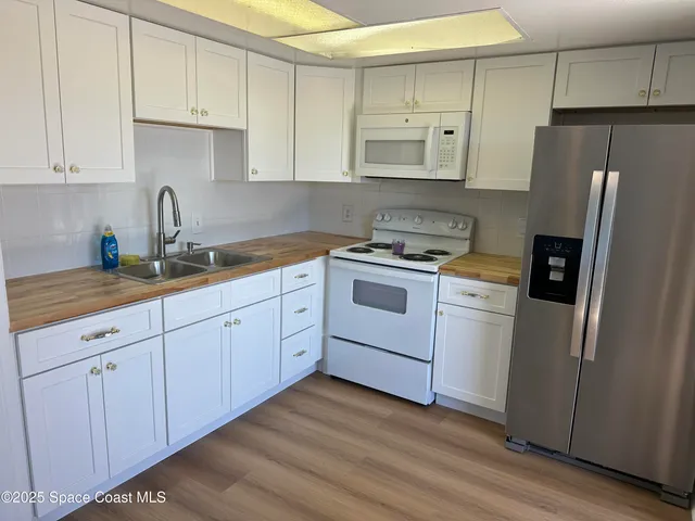 a kitchen with cabinets stainless steel appliances a sink and wooden floor
