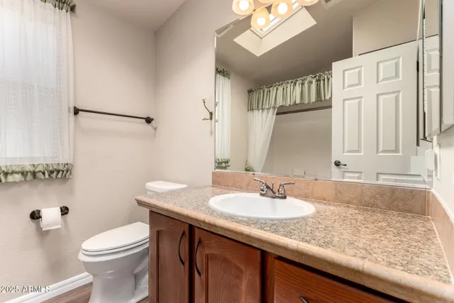 a bathroom with a granite countertop sink toilet and a mirror