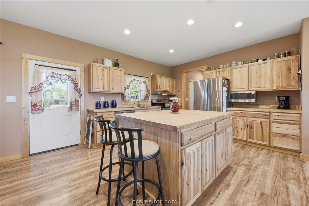 126 South Berlin Road Brenham, TX 77833 - Photo 13 of 30 a kitchen with kitchen island granite countertop wooden floors and white cabinets