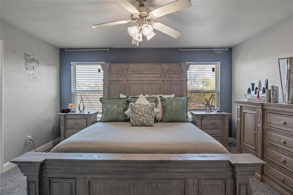 8342 Timberbrook Lane Dallas, TX 75249 - Photo 12 of 25 a large bed sitting in a bedroom next to a window and a chandelier