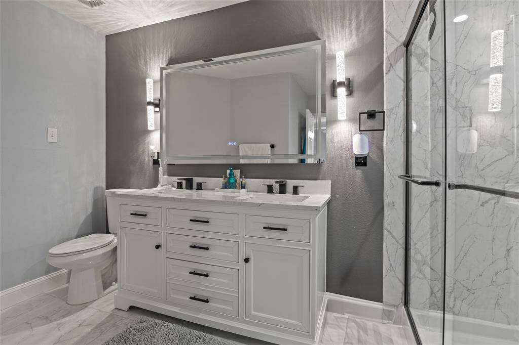 8342 Timberbrook Lane Dallas, TX 75249 - Photo 15 of 25 a bathroom with a granite countertop sink toilet a mirror a vanity and shower