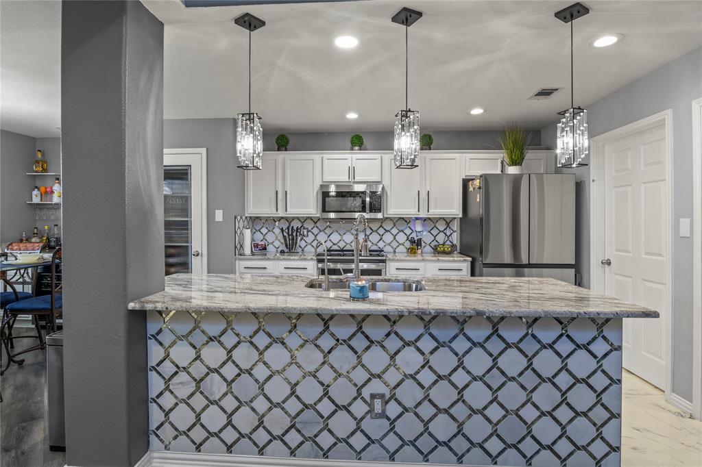 8342 Timberbrook Lane Dallas, TX 75249 - Photo 6 of 25 a large kitchen with granite countertop a large kitchen island in the center and stainless steel appliances