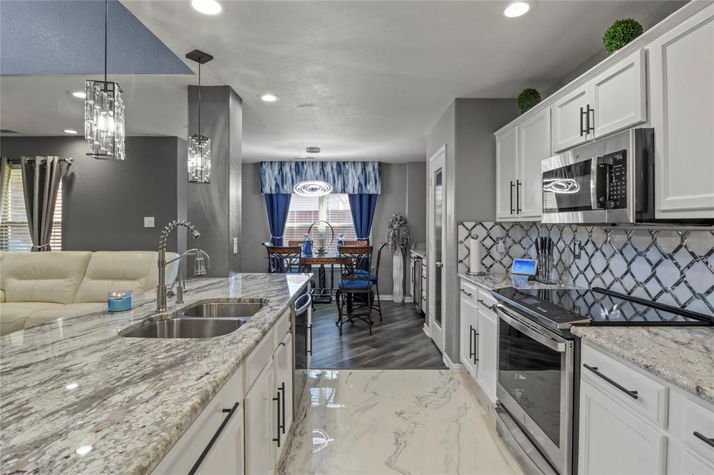 8342 Timberbrook Lane Dallas, TX 75249 - Photo 8 of 25 a kitchen with stainless steel appliances granite countertop a sink a stove and a refrigerator