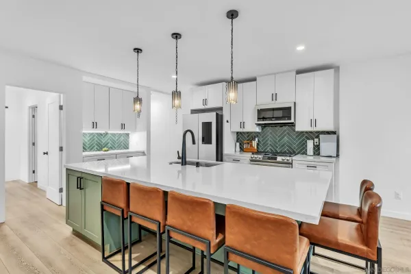 a kitchen with stainless steel appliances kitchen island granite countertop a table chairs and a refrigerator